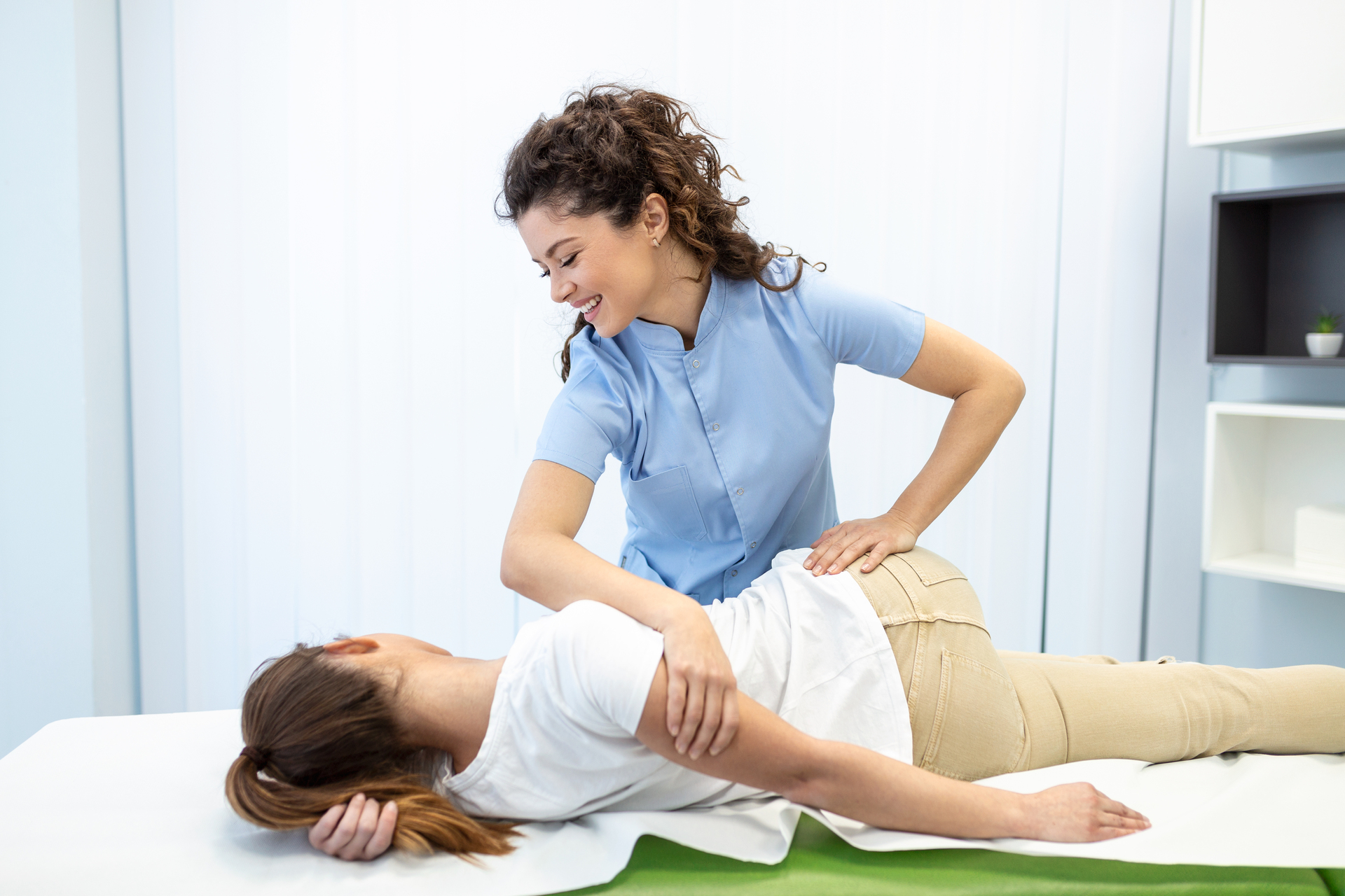 chiropractor giving an adjustment before recording visit in EHR software