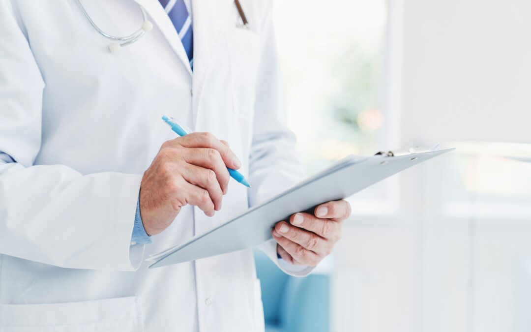 close up of a male chiropractor in a lab coat and clipboard reviewing cost savings of the chiropractic ehr software to manage his practice