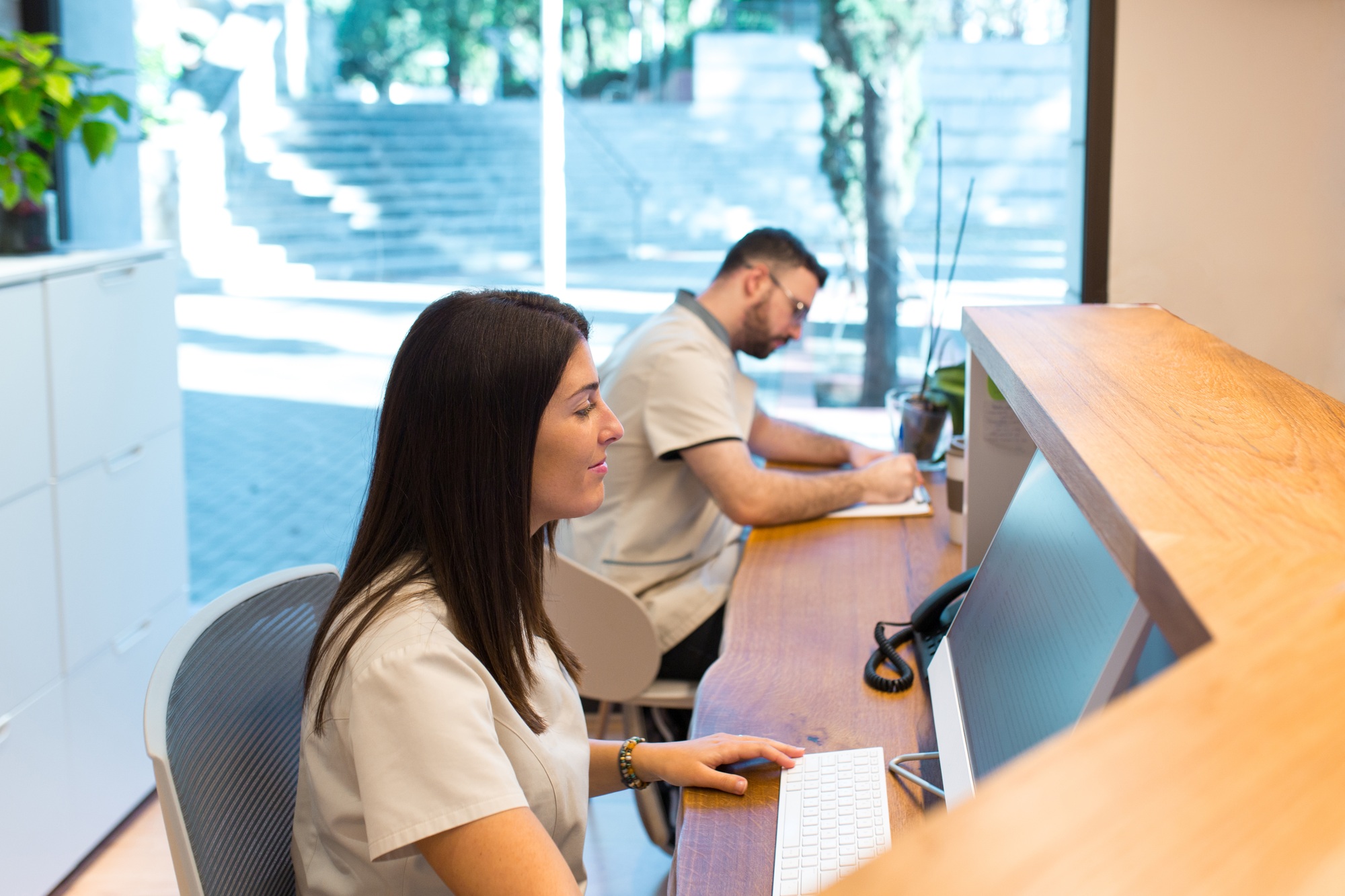 Two receptionists working at the front desk of a health center
