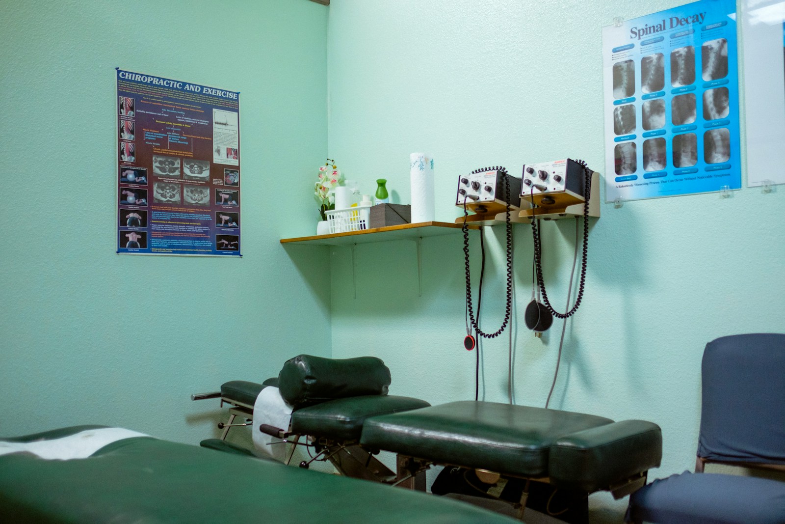 a chiropractic clinic room with a chair, shelf, and a poster on the wall - chiropractic startup guide